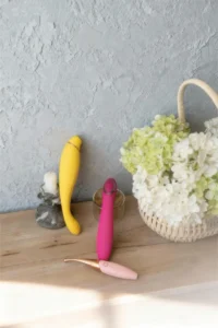 Pastel G spot vibrators styled on a wooden table beside a woven bag for a SheJournal feature on G spot vibrator products
