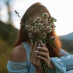 A woman holding wildflowers in soft evening light, symbolizing emotional awareness and self-growth, SheJournal blog visual