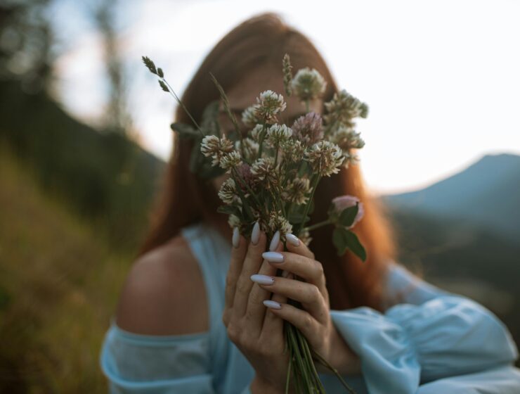 A woman holding wildflowers in soft evening light, symbolizing emotional awareness and self-growth, SheJournal blog visual