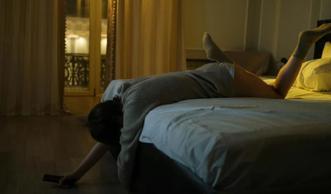 Exhausted young woman lying across the bed at night overwhelmed by 3AM anxiety