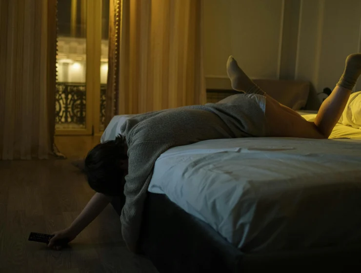 Exhausted young woman lying across the bed at night overwhelmed by 3AM anxiety